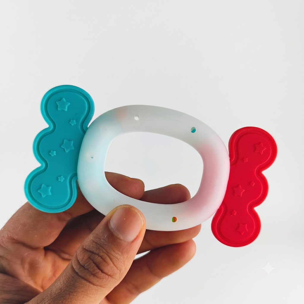 Hand holding a silicone teether with blue and red accents on a white background