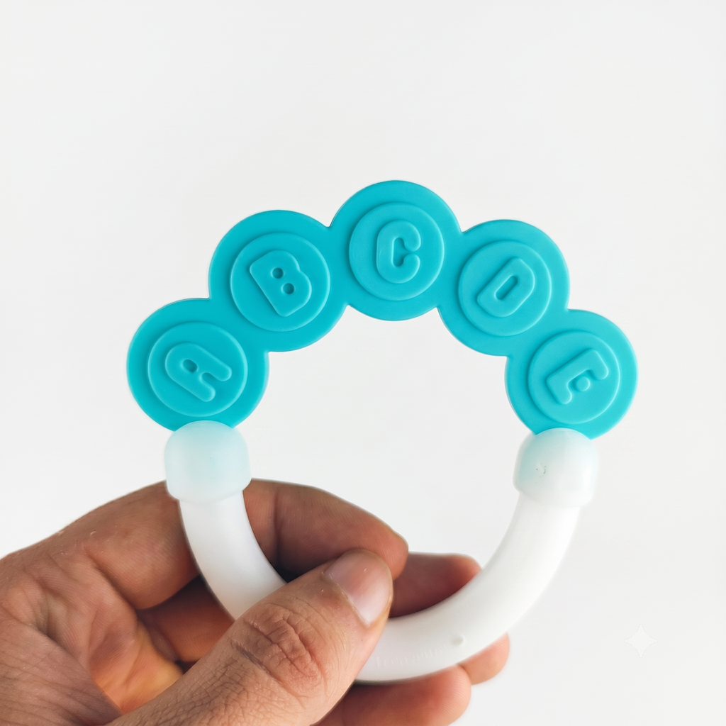 Teething ring with blue and white design held by a hand on a white background