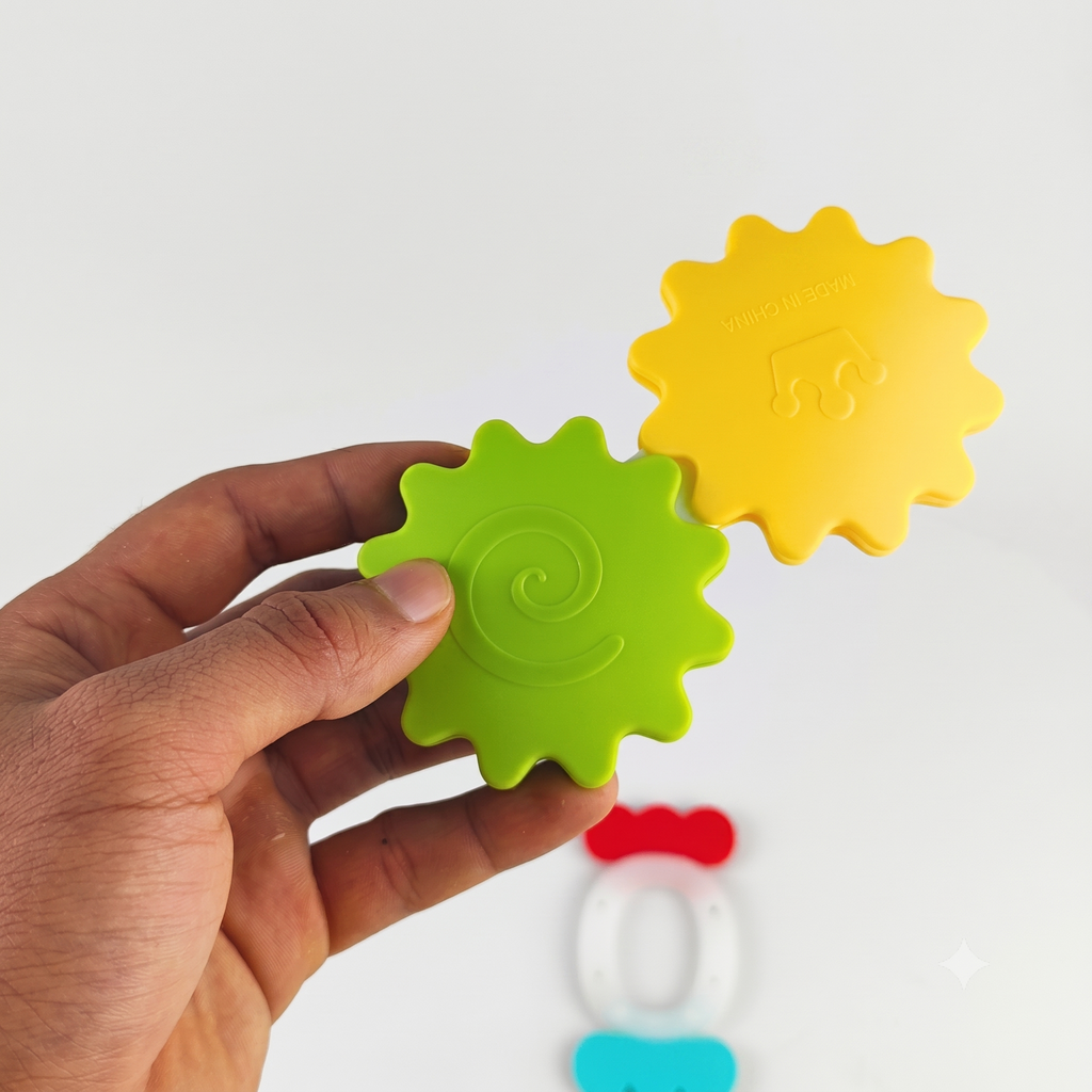 Hand holding a green gear-shaped toy with other colorful toys on a white background