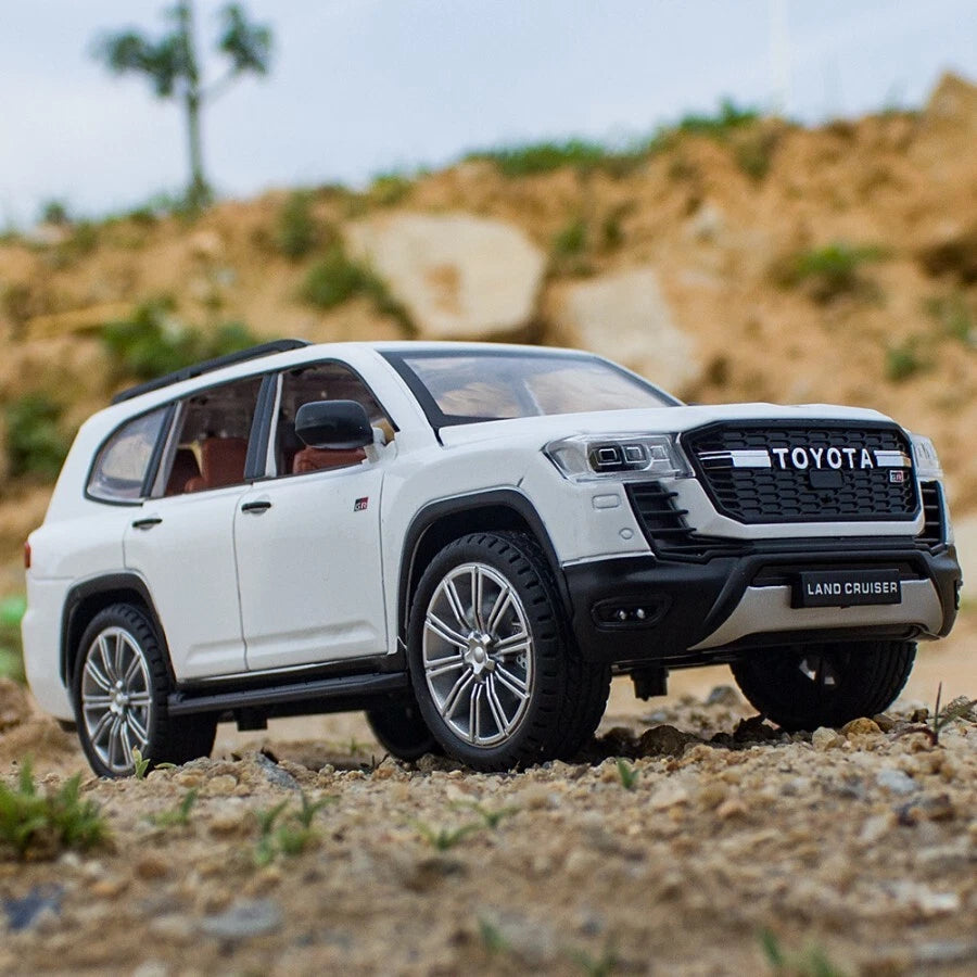 Model toy car of a Toyota Land Cruiser on a dirt surface with a blurred natural background