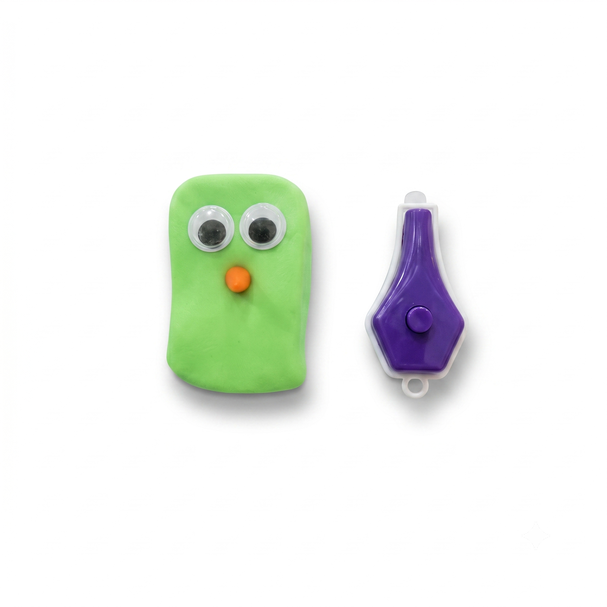 Green toy with googly eyes and an orange nose next to a purple tool on a white background