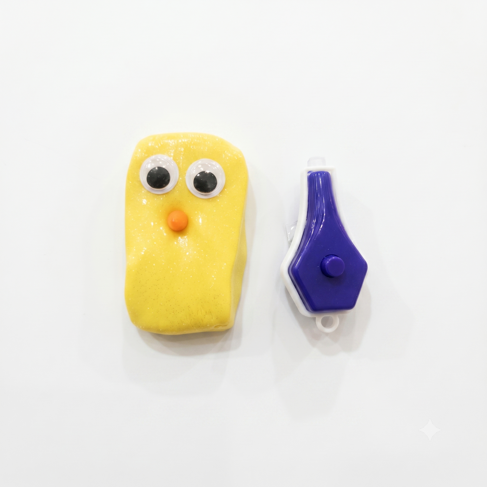 Yellow bird-shaped object with googly eyes and an orange beak, next to a purple and white device on a white background.