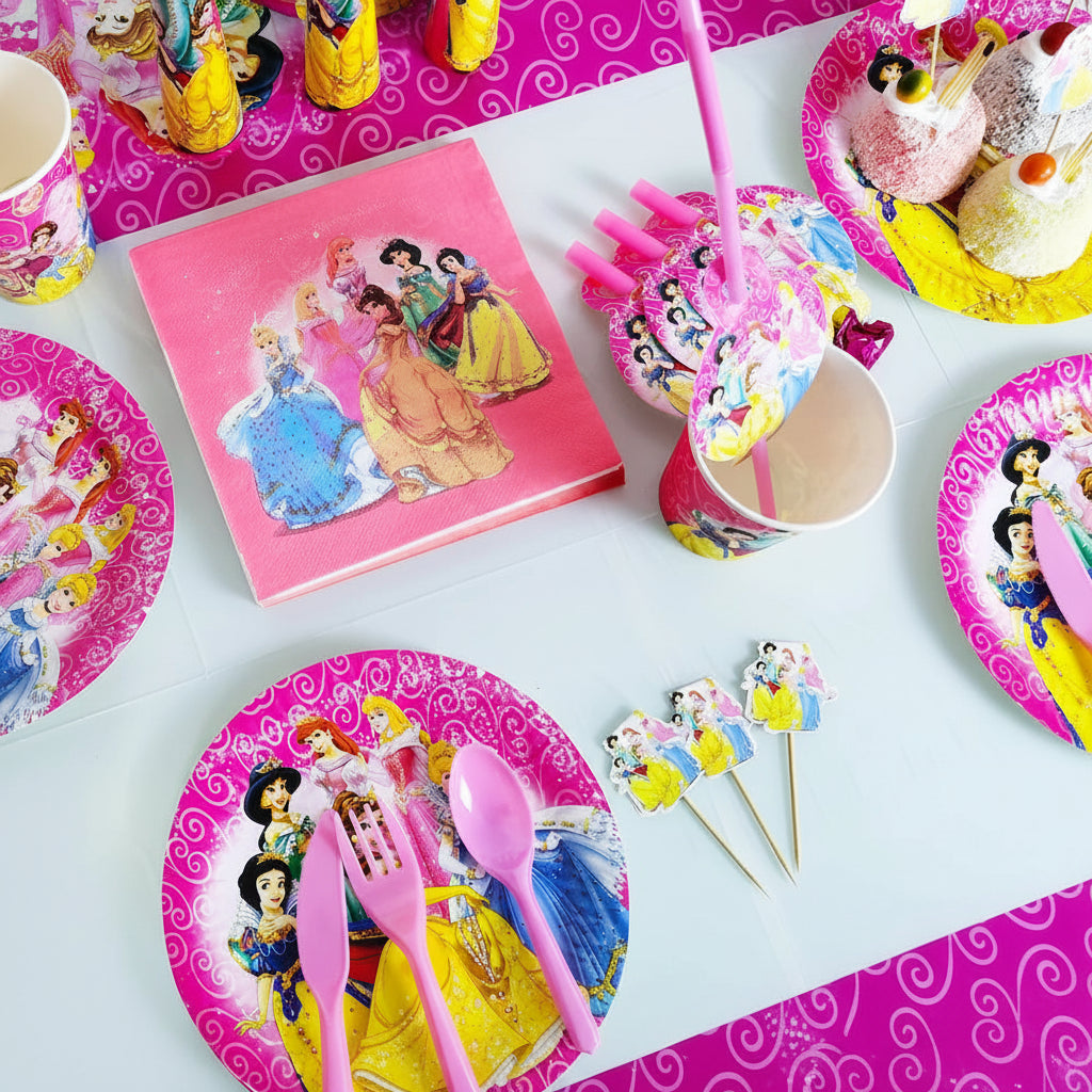 A Disney Princess party table setting with pink paper plates, napkins, cups, straws, spoons, and cake toppers featuring illustrated princess characters, arranged on a white tabletop.